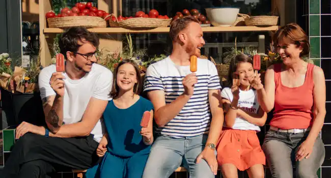 Des gens heureux mangent des glaces Hopopop devant le magasin general a Bruxelles